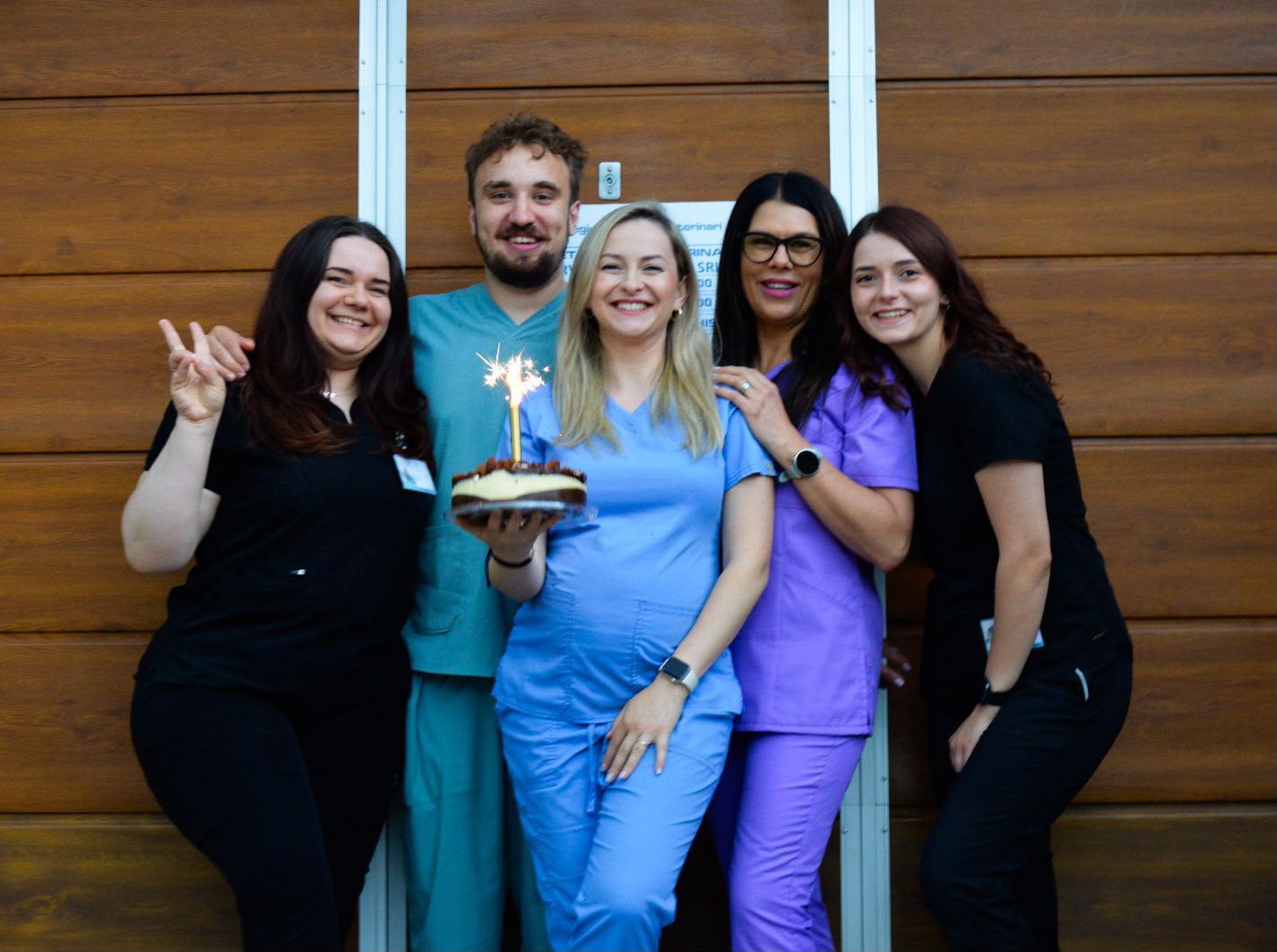 Echipa cabinetului veterinar, zâmbind, în fața ușii cabinetului